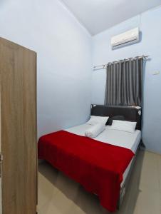 a bedroom with a bed with a red blanket at Homestay Pandan in Halangan