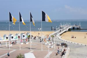 a view of a beach with flags and a pier at Grand H&ocirc;tel Richelieu in Arcachon