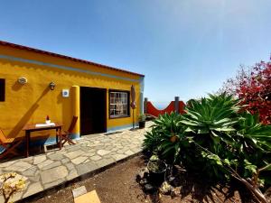 a yellow house with a table and some plants at Villa Asunción D in Breña Baja