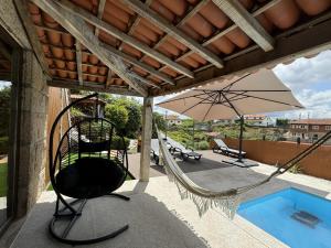 een terras met een schommel en een parasol en een zwembad bij Varandas do Tamega in Mondim de Basto