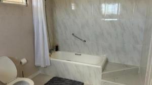 a white bathroom with a tub and a toilet at Welcome to Hope Winds, a charming property ranch-style house on a seren in Christ Church +13 photos