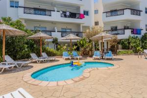 a swimming pool with chairs and umbrellas and a building at Artemis Cynthia Complex in Paphos City