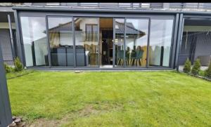 un'estensione in vetro di una casa con giardino di Apartament De LUX Wrzosowo Dziwnówek a Dziwnówek Altre 2 foto