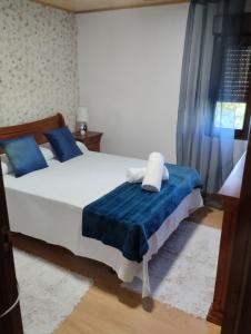 a bedroom with a white bed with blue pillows at Casa de Valeria in Tomiño