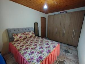 Un dormitorio con una cama con un edredón floral. en Casa Vista Verde, en Camanducaia