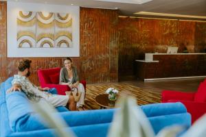 a man and a woman sitting on red chairs in a lobby at Lordos Beach Hotel & Spa in Larnaca
