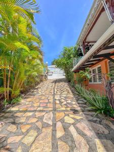 une passerelle en pierre à côté d'une maison avec des palmiers dans l'établissement Gran Bwa la villa west indies, à Sainte-Luce 10 autres photos
