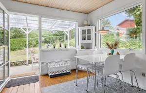 a dining room with a white table and chairs and large windows at 2 Bedroom Cozy Home In Allinge in Allinge