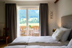 a bedroom with a bed and a view of a balcony at Maison d'h&ocirc;tes Ermitage in Chateau-d'Oex