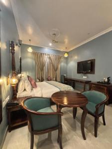 een slaapkamer met een bed, een tafel en stoelen bij The Kumbha Mahal Resort in Kumbhalgarh