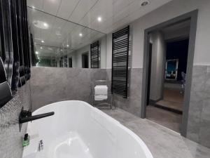 a bathroom with a white tub and a large mirror at Richmond Park Hotel in Boʼness