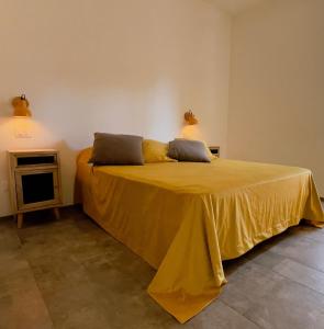 a bedroom with a yellow bed with two pillows on it at Tenuta Fascianello in Fasano