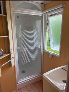 a glass shower in a bathroom with a window at Mobil-home au camping de bairon in Le Chesne