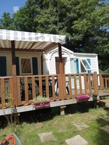 a tiny house with a porch and a deck at Mobil-home au camping de bairon in Le Chesne