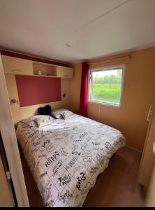 a bedroom with a bed with writing on it at Mobil-home au camping de bairon in Le Chesne