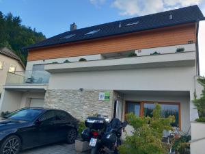 um carro e uma moto estacionados em frente a uma casa em Apartments Domovoj em Medvode