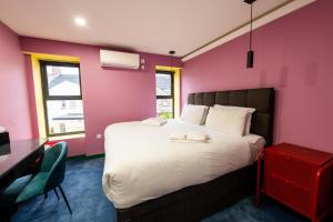 a bedroom with a large bed and a pink wall at Aaron Wise - 51 Fitzhamon Apartments in Cardiff