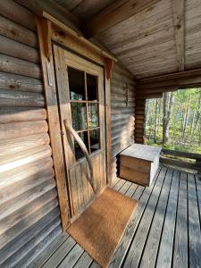 een veranda van een hut met een deur en een bank bij Metsäsydän mökki 4 Mettäpöyröö in Puumala