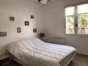 ein weißes Schlafzimmer mit einem Bett und einem Fenster in der Unterkunft Maison de vacance proche de la plage in La Brée-les-Bains