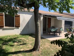 ein Haus mit einem Tisch und einem Baum im Hof in der Unterkunft Maison de vacance proche de la plage in La Brée-les-Bains