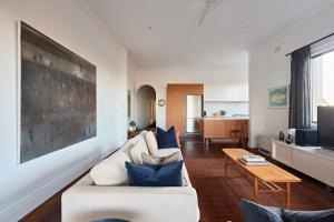 a living room with a white couch and blue pillows at Coogee Treetops in Sydney