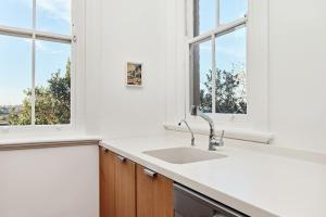 a kitchen with a sink and two windows at Coogee Treetops in Sydney +36 photos