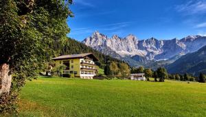 a house in a field with mountains in the background at Hotel Bergglück in Filzmoos