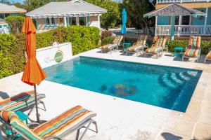 a swimming pool with chairs and umbrellas next to it at EMBRACE Resort in Staniel Cay