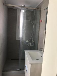 a shower with a glass door next to a sink at Bright and airy Village Studio Maisonette in Mytilinioí
