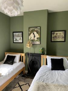 two beds in a room with green walls at Victorian Farrar Cottage in York +48 photos