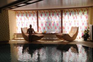 a woman sitting in chairs next to a pool of water at Hotel Central in Willingen