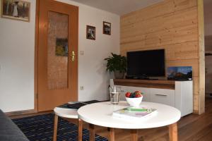 a living room with a white table and a tv at Gästehaus Eberhart in Bad Hindelang