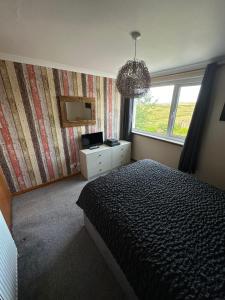 a bedroom with a bed and a window and a chandelier at Self Catering Spacious 2 Bed Apartment with sea views in South Erradale