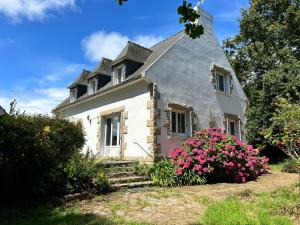 a white house with pink flowers in front of it at 763 - Maison bretonne en bord de mer in Erquy