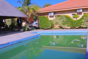 a swimming pool in front of a house at Okavango Roadside Guesthouse in Maun