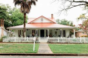 a white fence in front of a white house at Historic Garden Suite Walk to Bay and Downtown - Suite Two in Fairhope