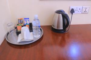 a table with a coffee pot and a bottle of water at Okavango Roadside Guesthouse in Maun