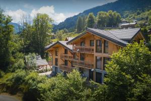 Una imagen de una casa de troncos con montañas al fondo. en MontCriou - OVO Network, en Samoëns