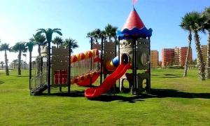 un parque infantil con tobogán en un parque con palmeras en شاليه بورتو جولف مارينا, en El Alamein