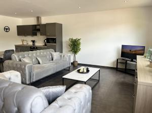 a living room with white couches and a kitchen at Loft à la Source in Francorchamps