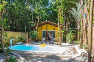 a pool in a backyard with a yellow house at Chalé Jacu Beach Pipa in Pipa