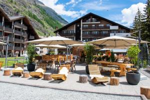 a hotel with tables and chairs and umbrellas at Schweizerhof Zermatt - a Small Luxury Hotel in Zermatt