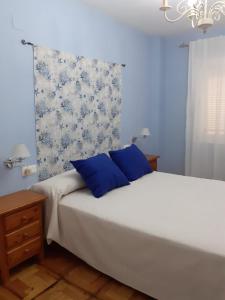 Un dormitorio con una cama con dos almohadas azules. en La casa familiar, en Puerto Real