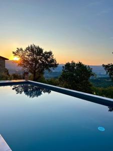 a swimming pool with a sunset in the background at Villa Lux Poggelleri vista unica sul Casentino in Poppi