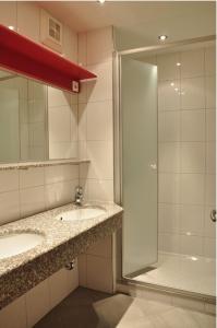 ヘルマゴルにあるPension Leitnerのバスルーム(洗面台2台、ガラス張りのシャワー付)