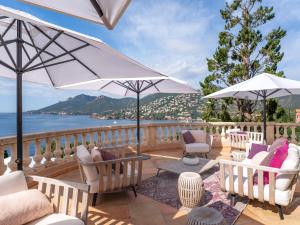 a patio with chairs and umbrellas overlooking the water at Tiara Yaktsa Côte d’Azur in Théoule-sur-Mer