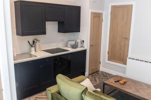una cucina con armadi neri e una sedia verde di Old Toy Shop - Cosy Flat in Central Hexham a Hexham