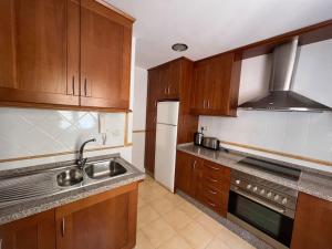 a kitchen with wooden cabinets and a sink and a refrigerator at GINVA - Dúplex en Plaza de España in El Puerto de Santa María