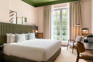 a hotel room with a large bed and a desk at Le Parchamp, a Tribute Portfolio Hotel, Paris Boulogne in Boulogne-Billancourt +167 photos