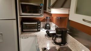 a kitchen counter with a microwave and a sink at Fantástico Flat no Laje de Pedra Mountain Village in Canela +60 photos
